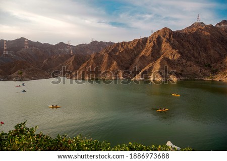 BEAUTIFUL AERIAL VIEW OF  BOATS, KAYAKS IN THE RAFIS WATER DAM  AT SUNSET TIME IN THE MOUNTAINS ENCLAVE REGION OF KHOR FAKKAN, SHARJAH UNITED ARAB EMIRATES Royalty-Free Stock Photo #1886973688