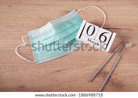 Wooden calendar with date 6 march, international day of the dentist, dental instruments, medical mask