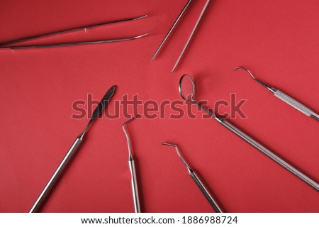 Metal dental instruments on a red background, top view