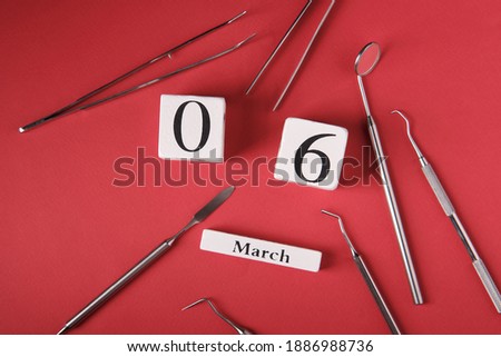 Wooden calendar with date 6 march, international day of the dentist, dental instruments