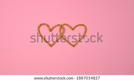 Gold shiny heart on gently pink background. St Valentine's day top view flat lay. Love romantic relationship concept. Copy space for text. The symbol of love and family.