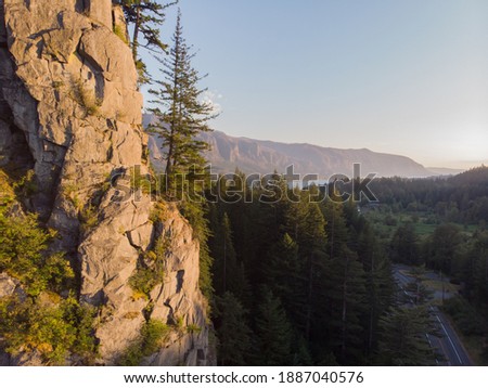 The rocky mountain with trees at clean blue sky background. Beautiful landscape with hills, river and forest. View from drone. Travel journal image. Wallpaper design.