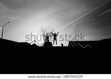 
silhouette of a man in a jump and his pet on the street