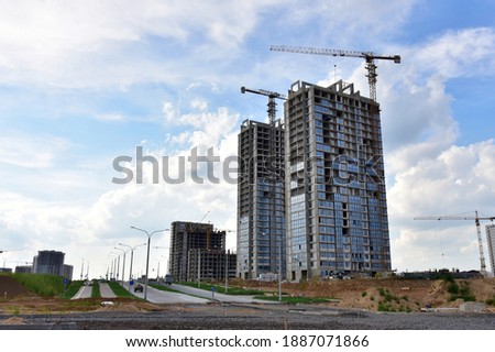 Tower cranes in action under buildings at construction site. Construction of the new modern residential buildings. Preparing to pour of concrete into formwork.