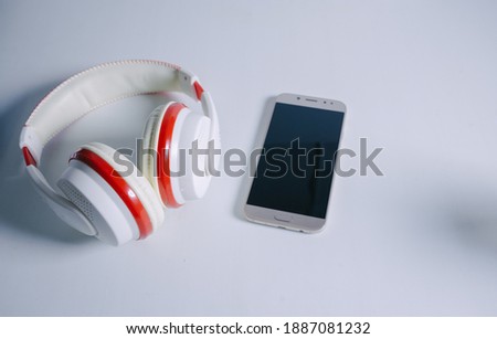 Mobile phone and wireless headphones lie on a white background. Listening to music or podcast concept