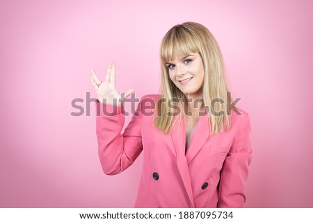 Young caucasian woman over isolated pink background doing hand symbol