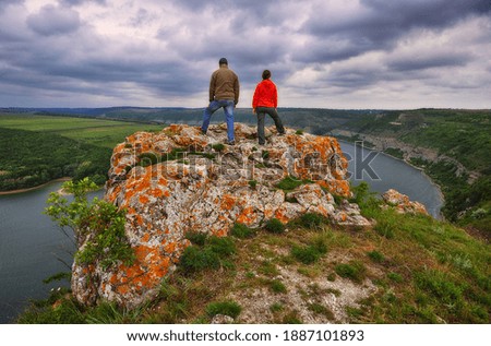 couple of tourists on the rock. a man and a woman look at the picturesque river canyon