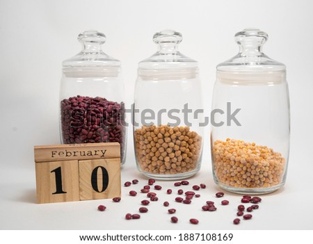 Сalendar February 10 is the day of legumes. beans, chickpeas and peas in jars in the background.