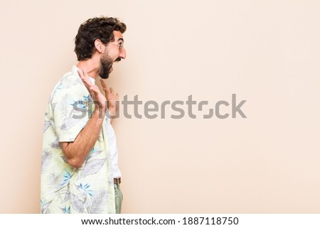 young cool bearded man surprised or shocked and looking to the s