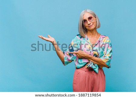 middle age cool woman smiling proudly and confidently, feeling happy and satisfied and showing a concept on copy space