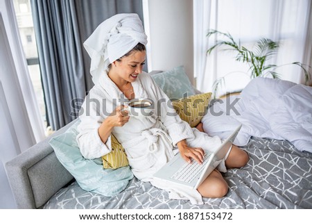 Young woman with laptop lying on bed indoors at home, relaxing. Woman checking social apps and working. Communication and technology concept 