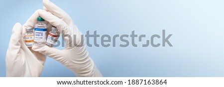 Potential vaccination for COVID-19 concept. Beautiful banner - hands of Researcher holding Coronavirus 2019-nCoV Vaccine vials on blue hygienic tone background. Hope, Success, COVAX, Collaboration. Royalty-Free Stock Photo #1887163864