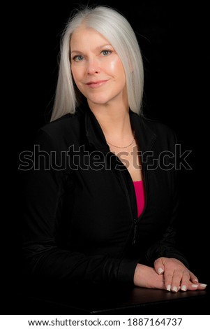 Image of a beautiful mature woman in a business attire. Shot with a black background. This woman is your boss.