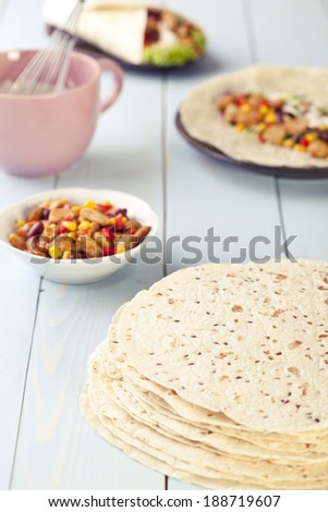 tortilla wraps with meat and vegetables on blue wood board