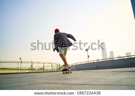 teenage asian child skateboarding outdoors on a pedestrian bridge