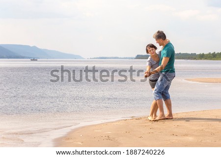 beautiful sporty mature couple dancing on the beach on the Volga river against the background of the Zhiguli mountains on a summer day