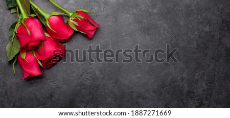 Valentines day greeting card with red rose flowers bouquet over dark stone background. Top view flat lay with space for your greetings