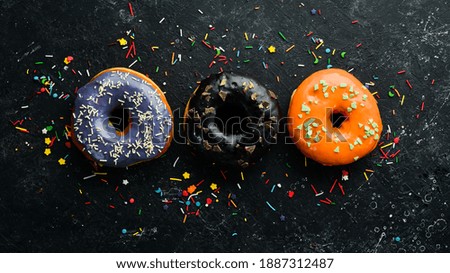 Colored sweet baked donuts on a black background. Top view. Rustic style.