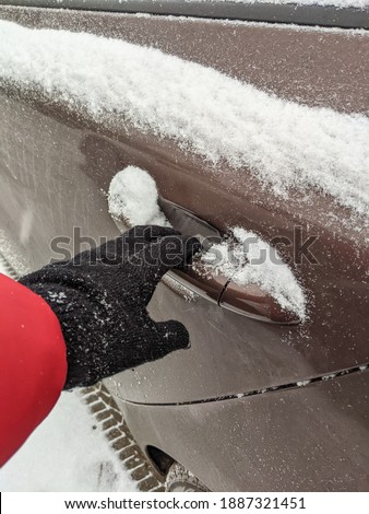 woman in gloves opens the car door covered with snow. snowy winter. hand close-up
