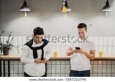 chat in the social network new app. two friends are standing in a cafe. print a message in the phone.