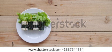 Salad roll on a white plate. Put on a brown wooden pallet.