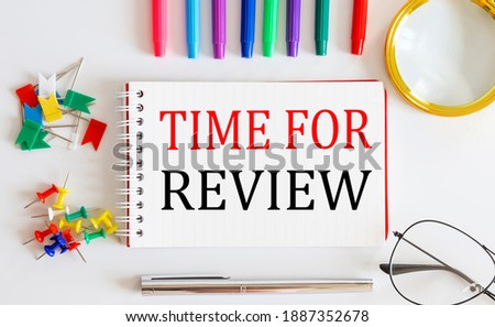 Notebook with TIME FOR REVIEW word with office tools on white table.