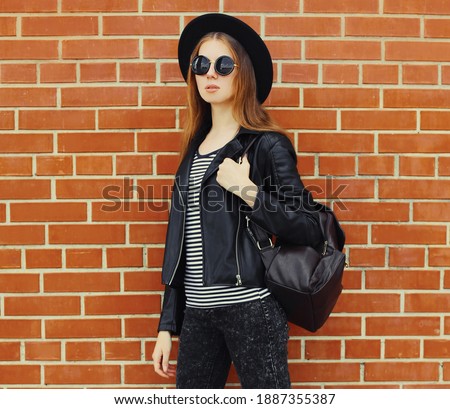 Portrait of stylish young woman model wearing a black rock style over a brick wall background