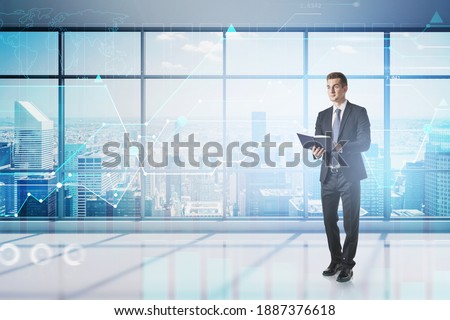Full length portrait of young European businessman with planner standing in office. Concept of scheduling. Toned image double exposure. Elements of this image furnished by NASA