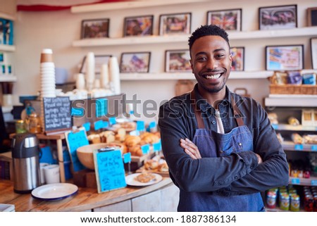 Portrait Of Smiling Male Owner Of Coffee Shop Standing By Counter Royalty-Free Stock Photo #1887386134