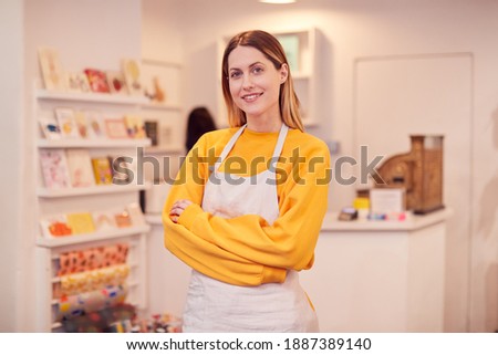 Portrait Of Smiling Female Small Business Owner Standing Inside Shop On Local High Street Royalty-Free Stock Photo #1887389140