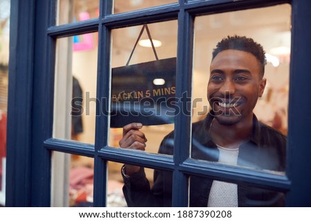Smiling Small Business Owner Turning Around Back In 5 Minutes Sign On Shop Or Store Door Royalty-Free Stock Photo #1887390208