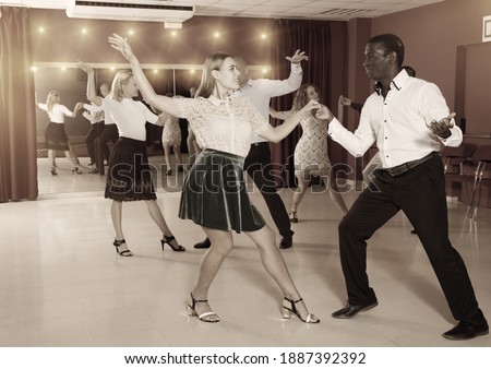 Young positive people dancing rock-and-roll in pairs .. Royalty-Free Stock Photo #1887392392
