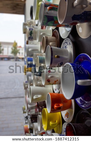 Coffee and thea cups hanging on the wall divers selection with a variety colors