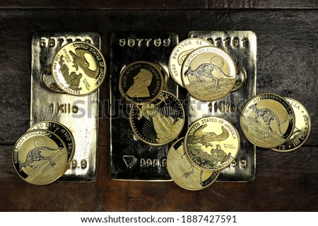 gold ingots an various bullion coins on wooden background