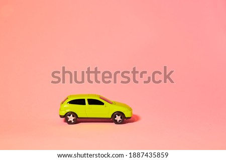 yellow toy car on a pink background, a concept idea of a taxi and delivery of goods during quarantine.