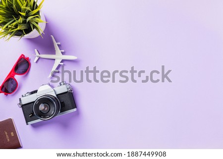 Top view flat lay mockup of retro camera films, airplane, sunglasses traveler accessories isolated on a purple background with copy space, Business trip, and vacation summer travel concept