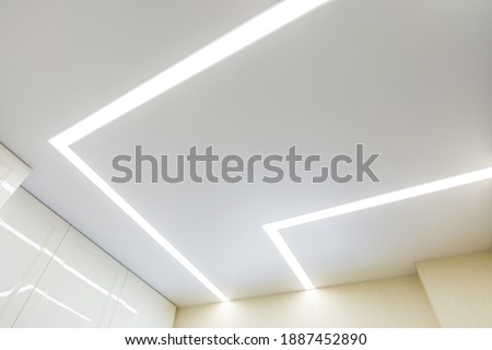 suspended ceiling with halogen spots lamps and drywall construction in empty room in apartment or house. Stretch ceiling white and complex shape. Royalty-Free Stock Photo #1887452890