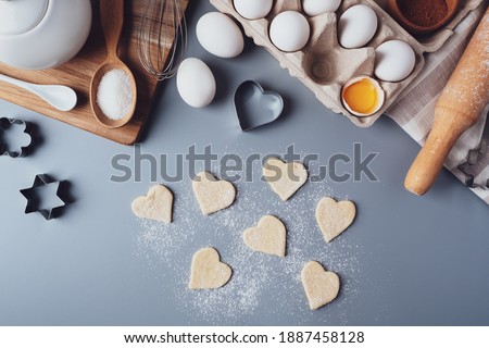 Cookies in the shape of hearts. Ingredients for making homemade cookies on a gray background. The concept of cooking sweets for Valentine's day, Father's Day or Mother's Day. Flat lay, top view.
