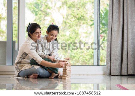 Playful mother and daughter having fun each other at home