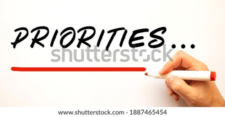 Hand writing PRIORITIES with red marker. Isolated on white background. Business concept.