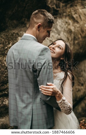 Portrait of a young beautiful couple of man and woman in a white wedding dress and suit walking in the stone gorge. Wedding day in nature, ceremony, photo shoot, happiness, love. Canyon, mountains.