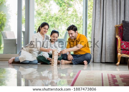 Happy Family sitting On floor Playing With The Wooden Blocks At Home Royalty-Free Stock Photo #1887473806