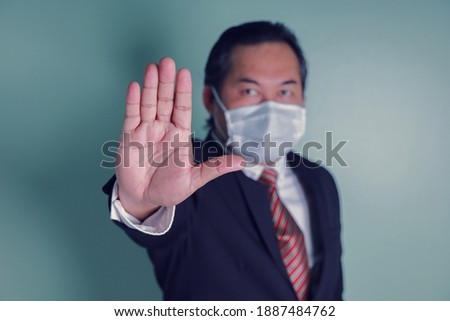 Portrait close up at to hand businessman showing the stop sign. Asian businessman portrait wears a black suit wearing medical masks. Concept health care protect covid-19.