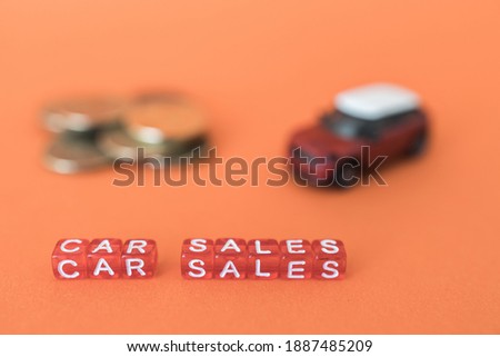 car sale from red cubes in the foreground, blurred red auto background and money
