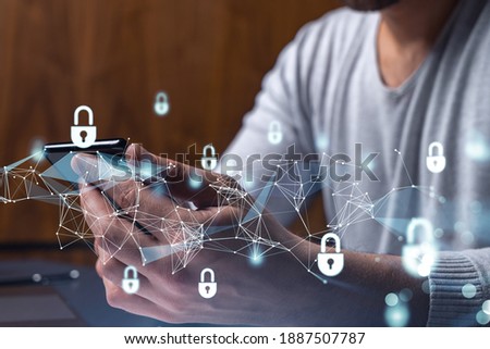 A programmer is browsing the Internet in smart phone to protect a cyber security from hacker attacks and save clients confidential data. Padlock Hologram icons over the typing hands. Royalty-Free Stock Photo #1887507787