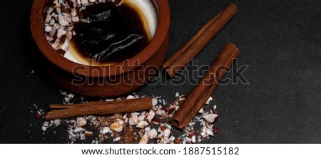 Turkish traditional dessert in earthenware casserole with cinnamon sticks and hazelnut; sutlac. Baked Rice Pudding. Panoramic close-up macro shot. Panorama banner. High resolution sharp photo.