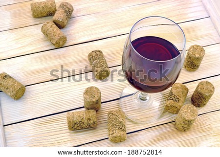 Glass of wine on background of corks and wooden slats 