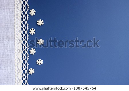 Festive romantic blue background with white lacy border and small sugar snowflakes, copy space for text. Background for greeting card