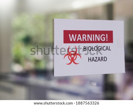 The warning sign "Biological Hazard” for warning infected biohazard area, a safety sign warning on a front door of laboratory room. Royalty-Free Stock Photo #1887563326
