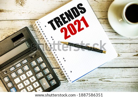 TRENDS 2021 written on white paper near coffee and calculator on a light wooden table. Business concept